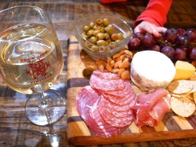charcuterie board with wine and hand reaching toward board